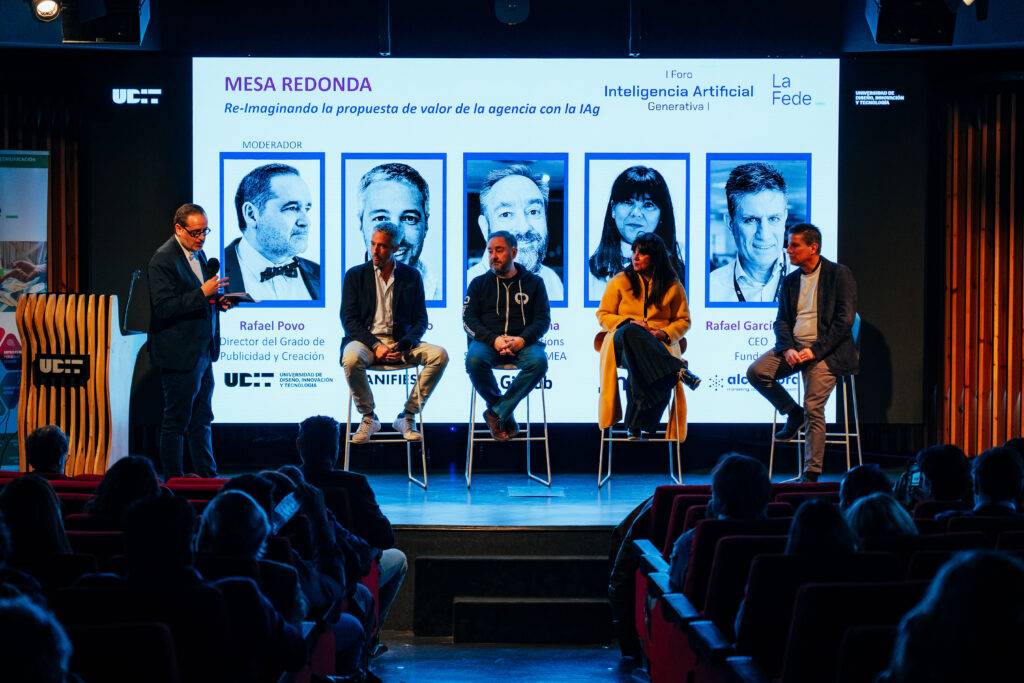 Una mesa redonda sobre inteligencia artificial con varios ponentes presentando en un escenario.