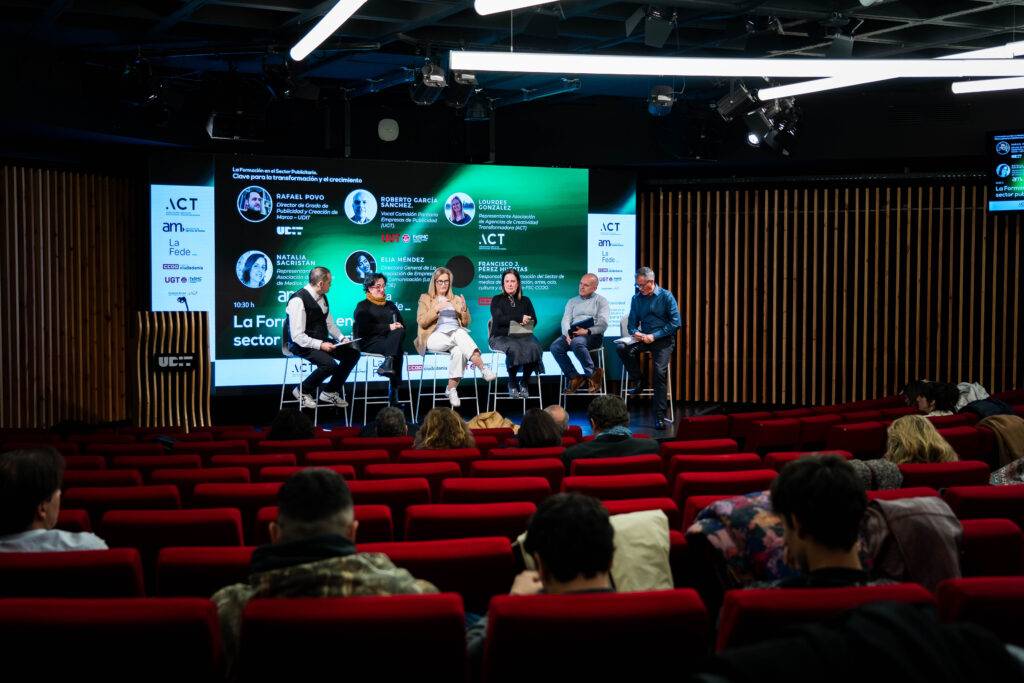 Un panel de discusión en un evento con varios participantes sentados frente a una audiencia.