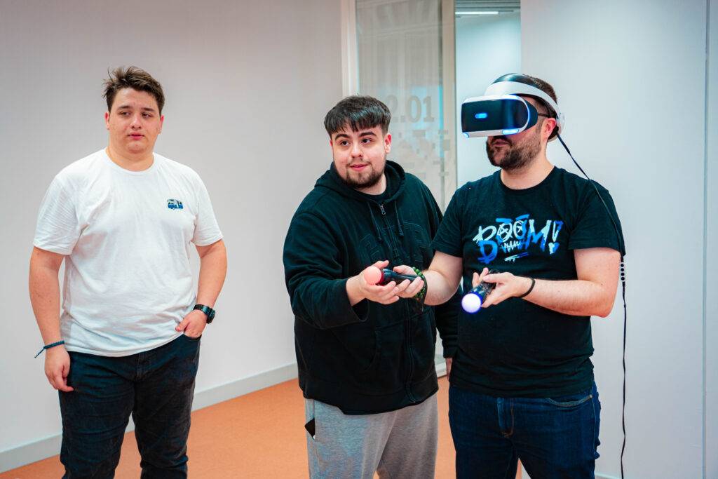 Tres jóvenes participan en una actividad de realidad virtual en una sala moderna.