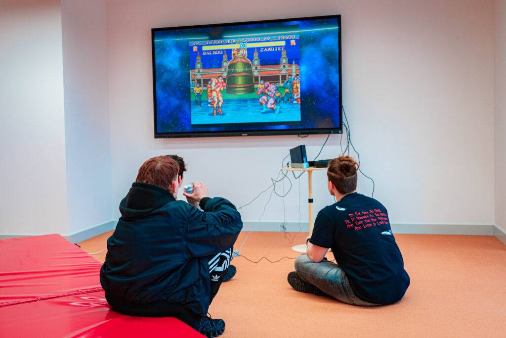 Dos personas están jugando a un videojuego en una sala con un televisor grande.