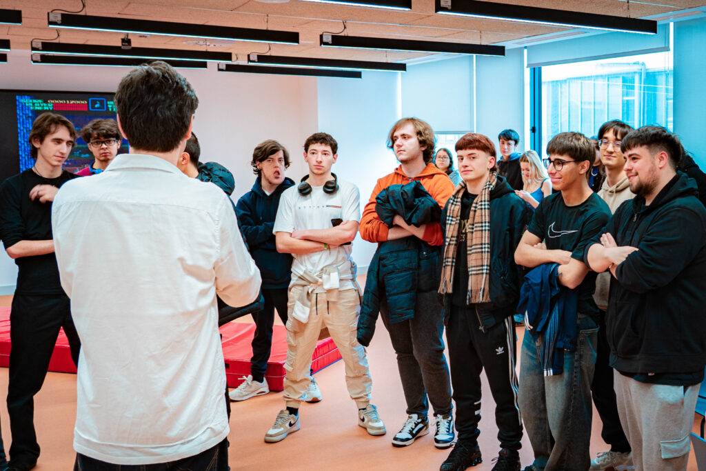 Un grupo de jóvenes observa atentamente a un orador en un ambiente moderno.