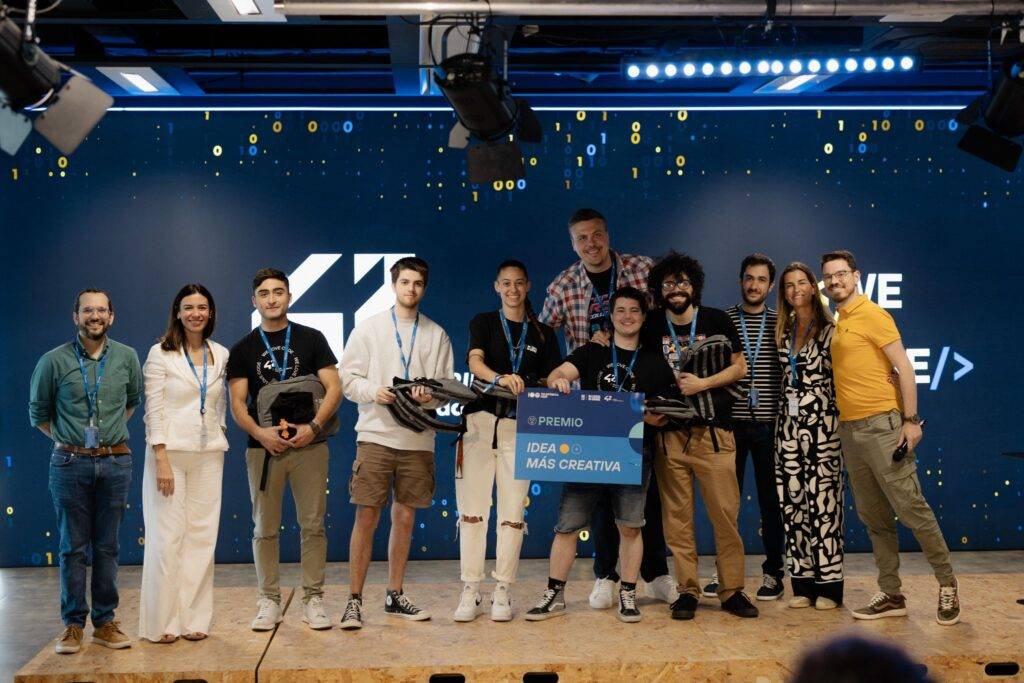 Un grupo de personas en un evento, sosteniendo un premio al lado de un fondo decorativo.