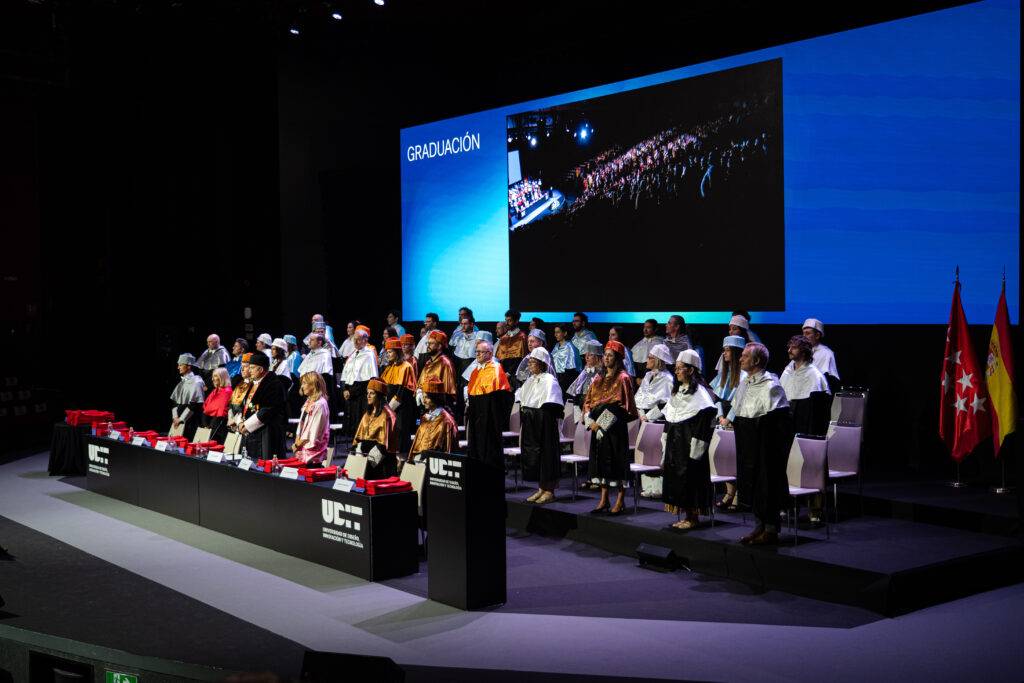 Ceremonia de graduación con un grupo de personas en un escenario formal.