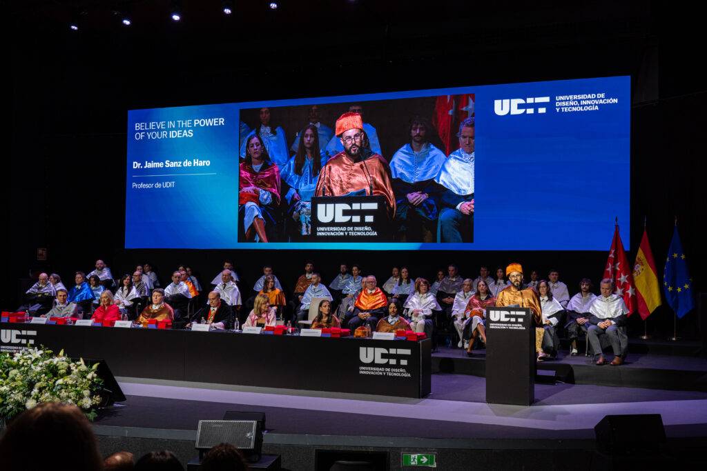 Una ceremonia académica con varios oradores y una presentación en pantalla.