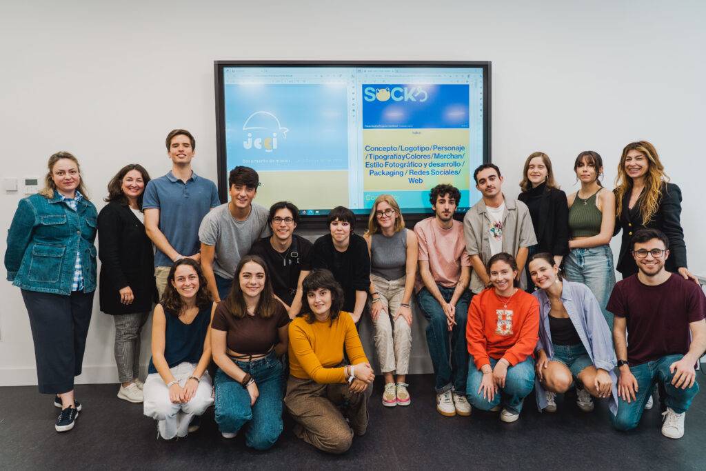 Grupo de personas posando frente a una pantalla con un logo y texto relacionados con un proyecto.