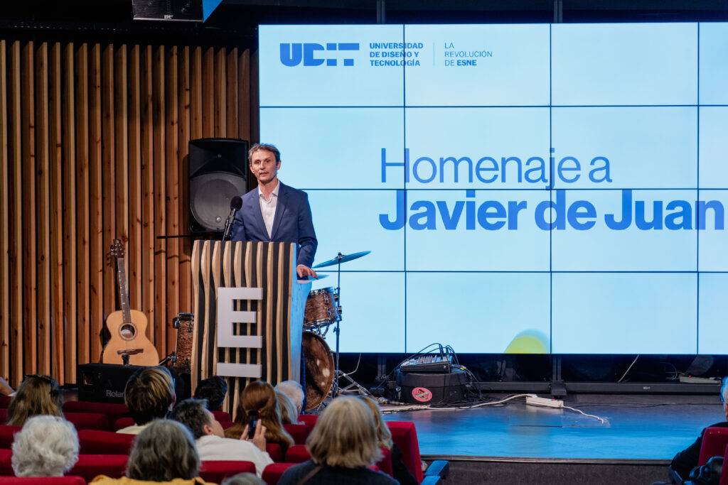 Un evento de homenaje a Javier de Juan en un auditorio con una presentación en pantalla.