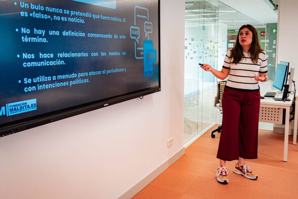 Una mujer presenta información sobre noticias falsas en una sala de conferencias.