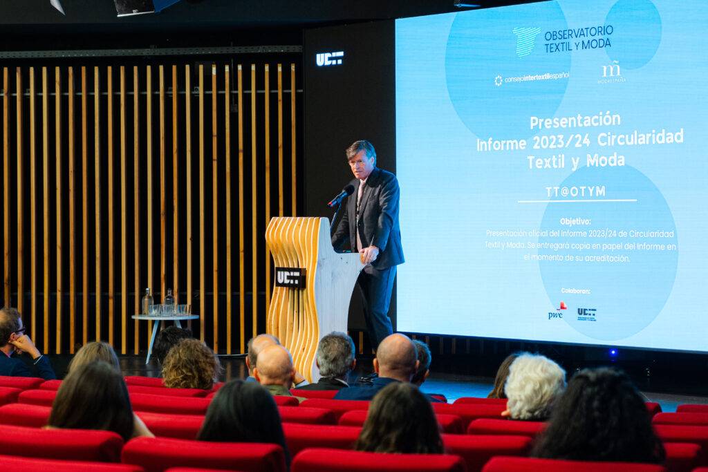 Un ponente está dando una presentación sobre el informe de circularidad en el sector textil y moda en un auditorio.