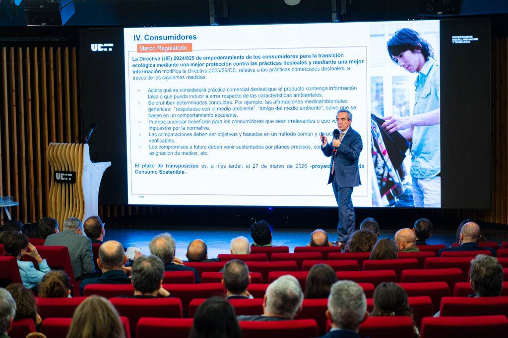 Una presentación en un auditorio con un conferencista y una audiencia sentada frente a una pantalla.