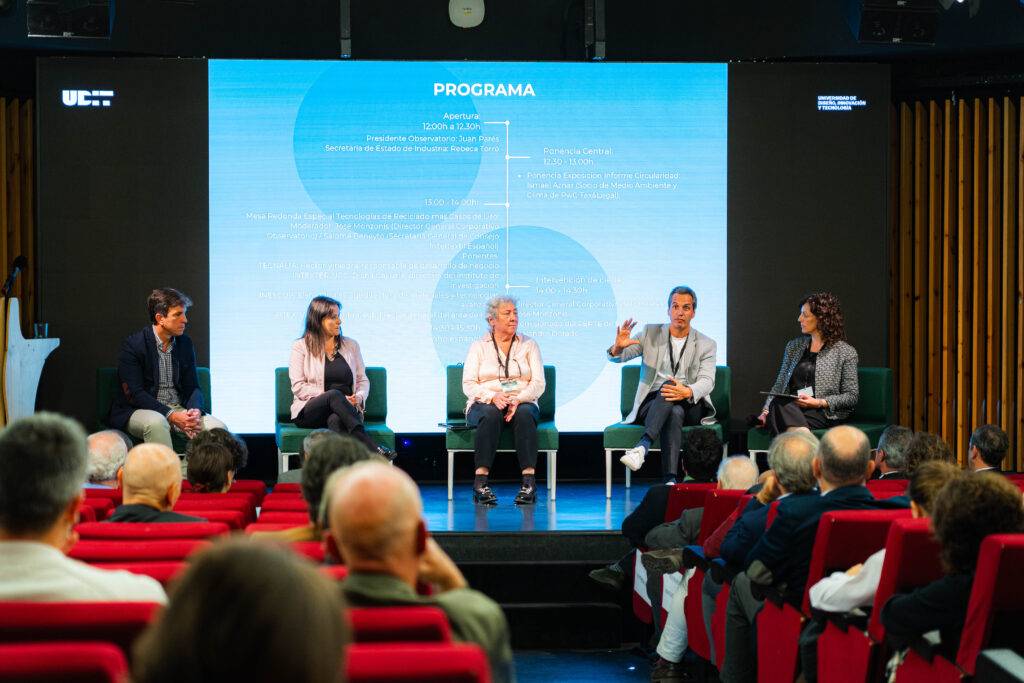 Un panel de discusión con varios ponentes sentados en un escenario frente a una audiencia.