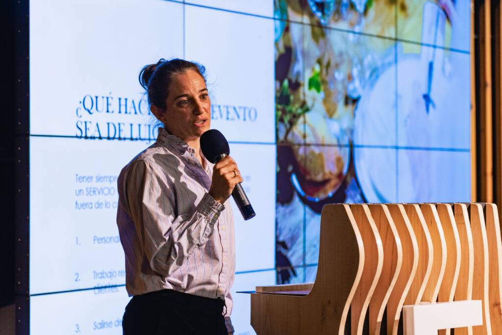 Una persona está dando una charla en un evento mientras sostiene un micrófono.