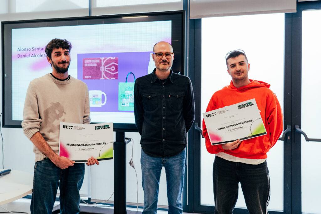Tres hombres posan juntos sosteniendo diplomas en un evento de entrega de premios.