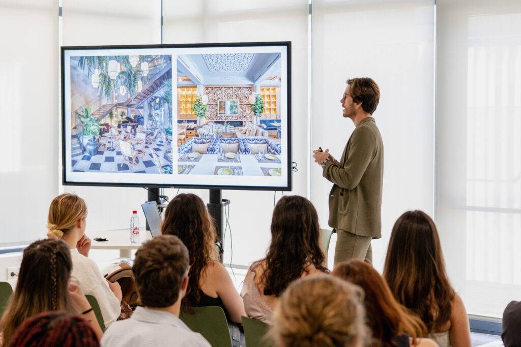 Un presentador está mostrando un diseño de interiores a un grupo de personas en un espacio moderno.