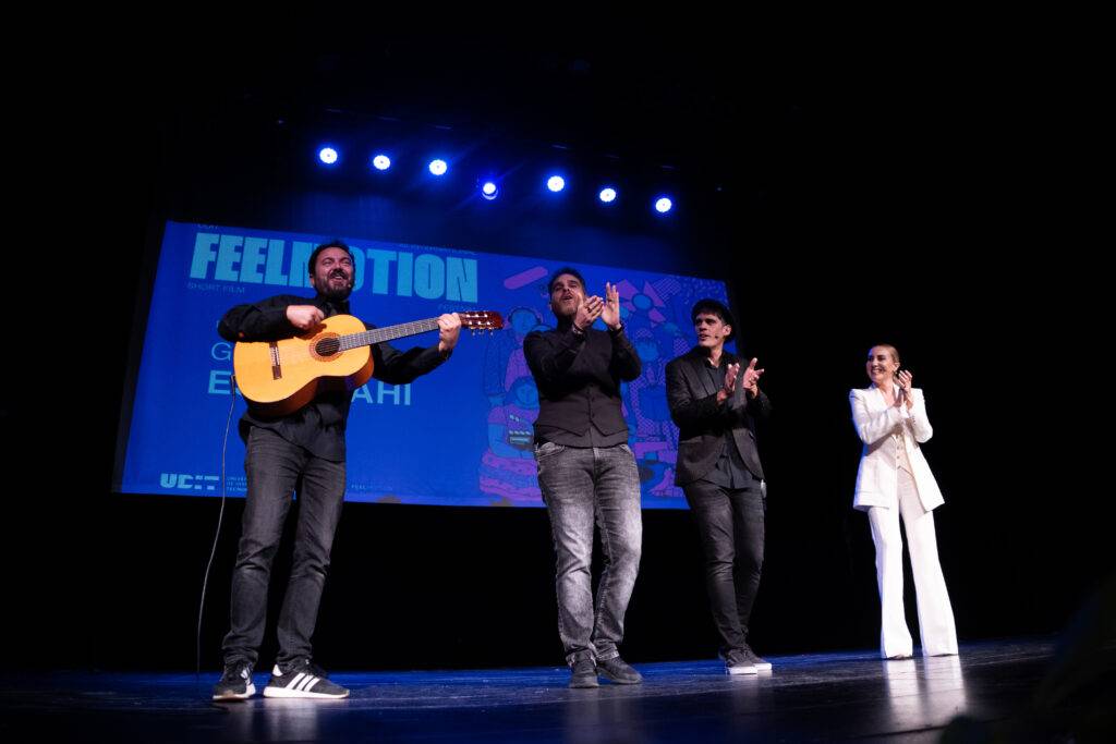 Un grupo de músicos actuando en un escenario mientras el público aplaude.