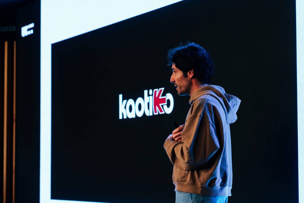 Una persona de pie frente a una pantalla que muestra el logo de kaodiK.