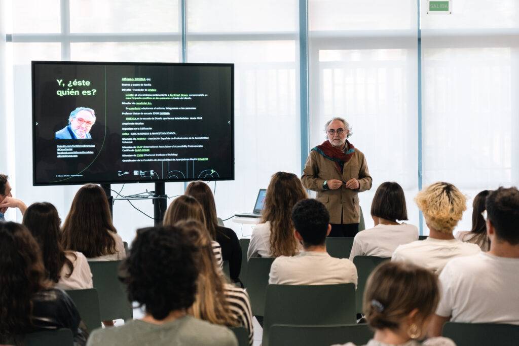 Una persona presenta una conferencia ante un grupo de estudiantes en un aula moderna.