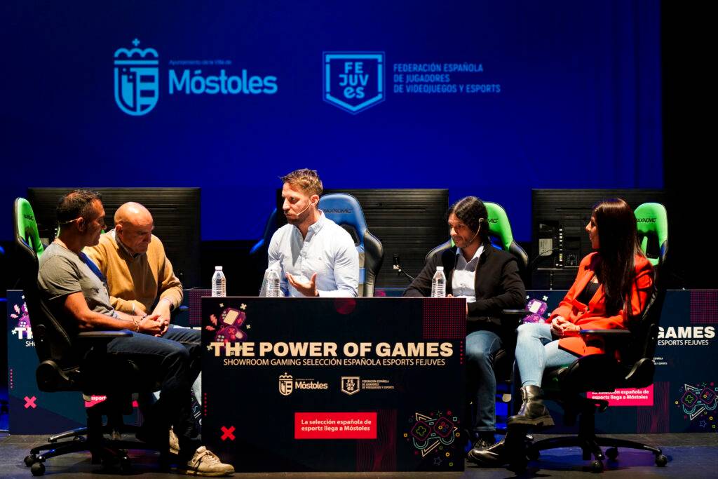 Un grupo de personas discutiendo en un evento sobre videojuegos y esports.