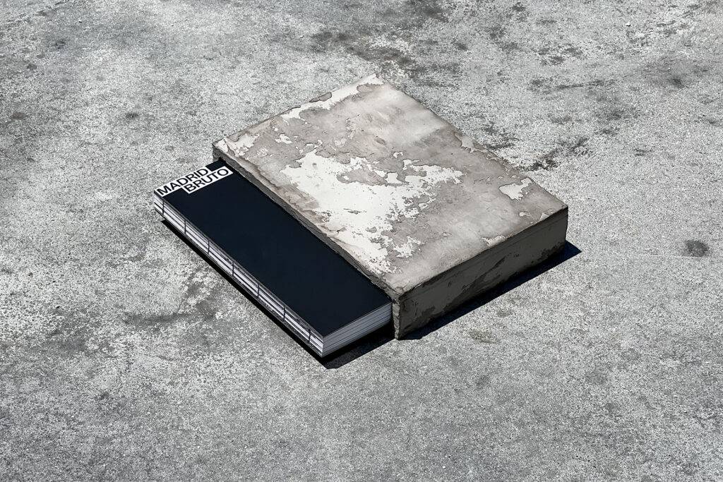 Un libro que parece estar tapado por un objeto de cemento sobre una superficie gris.