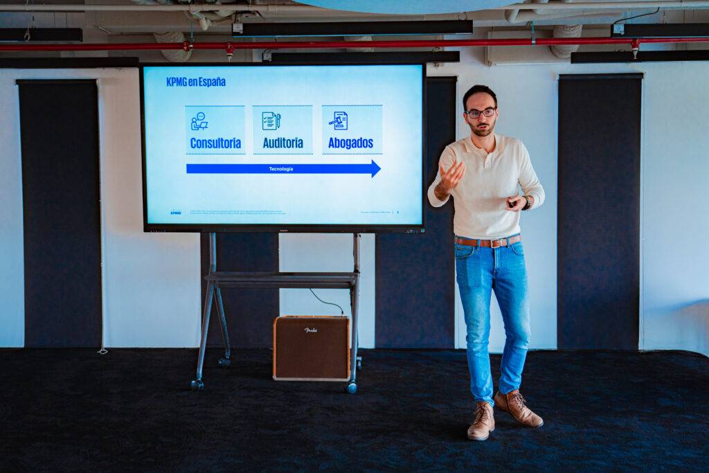 Un hombre presenta información sobre KPMG en España en una sala moderna.