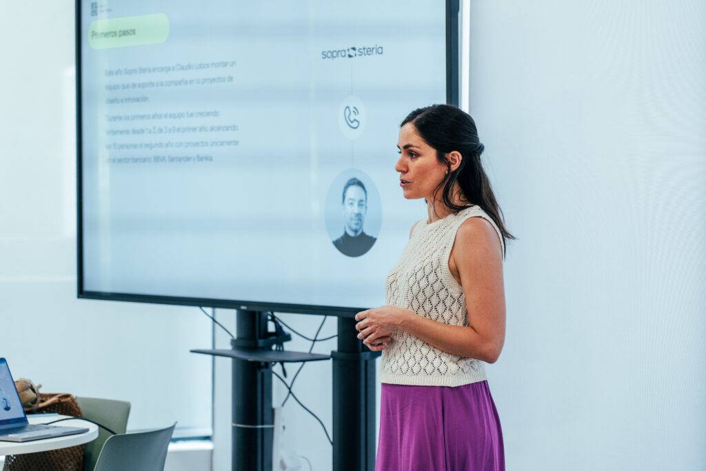 Una mujer presenta información frente a una pantalla en una sala de reuniones.