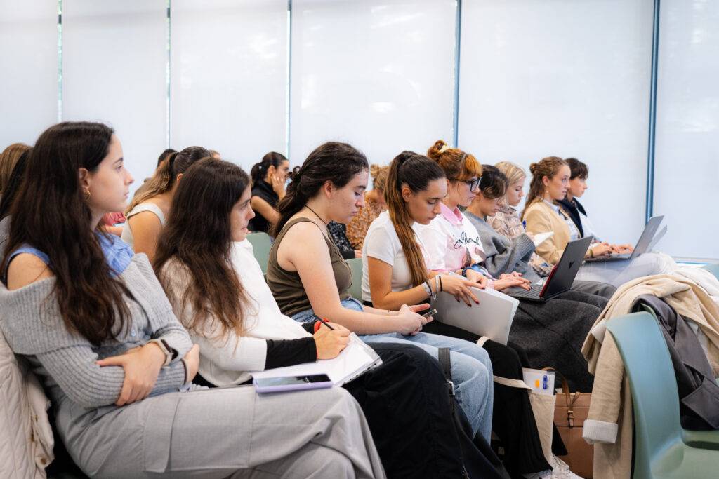 Un grupo de jóvenes sentado en un salón, prestando atención durante una presentación.