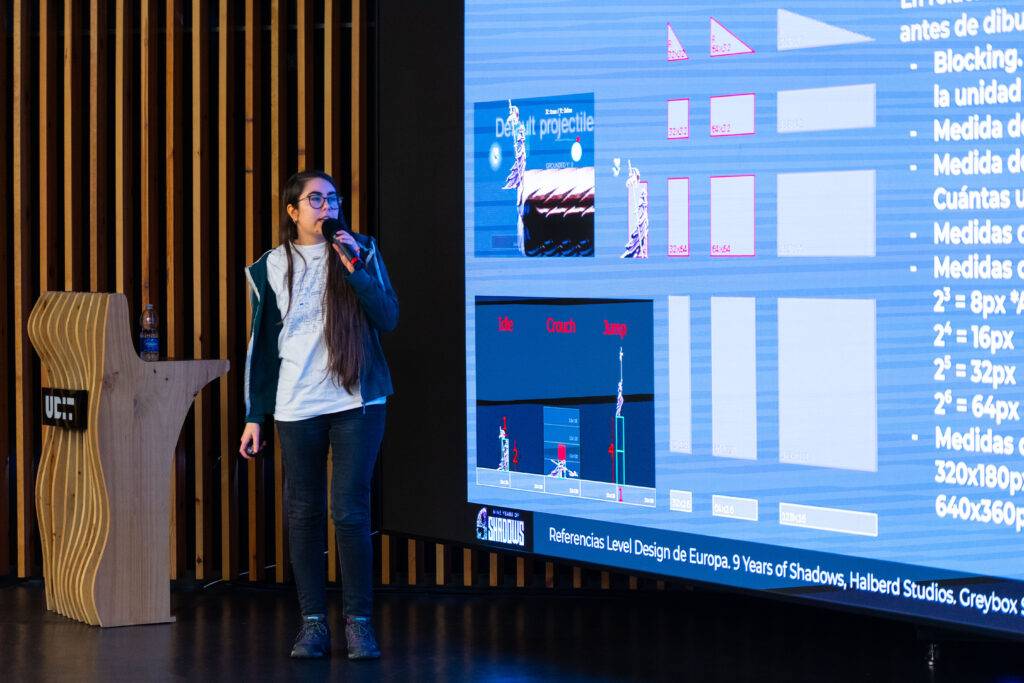 Una presentadora se encuentra explicando un tema relacionado con el diseño en una sala de conferencias.