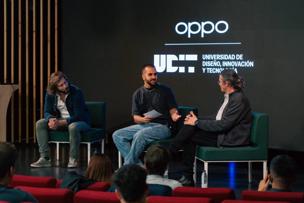 Un panel de discusión en una universidad con tres hombres sentados en un escenario.