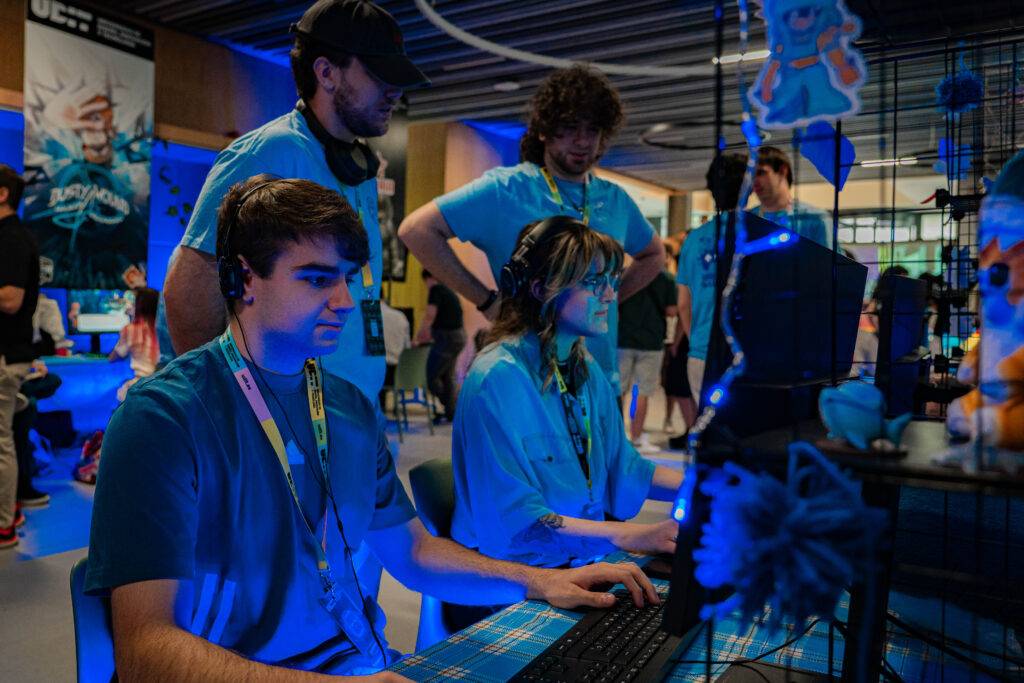 Un grupo de jóvenes con camisetas azules interactúa en un evento de videojuegos.