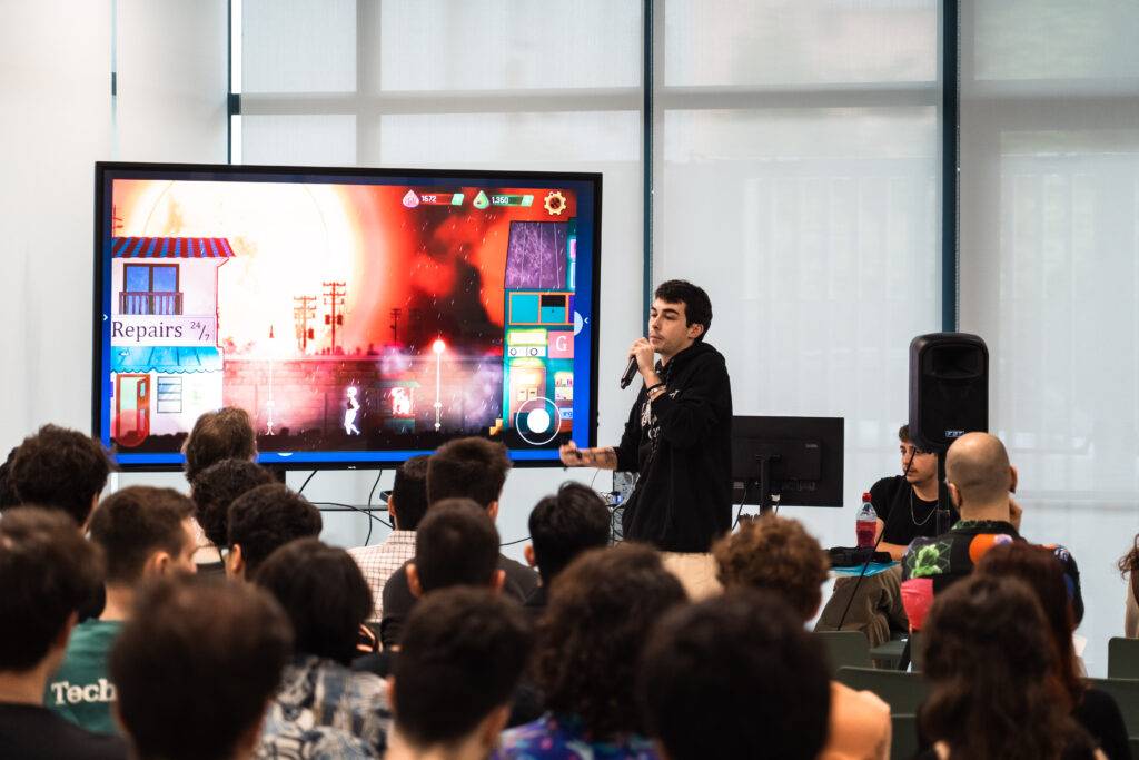 Una persona presenta un videojuego en una conferencia ante una audiencia numerosa.