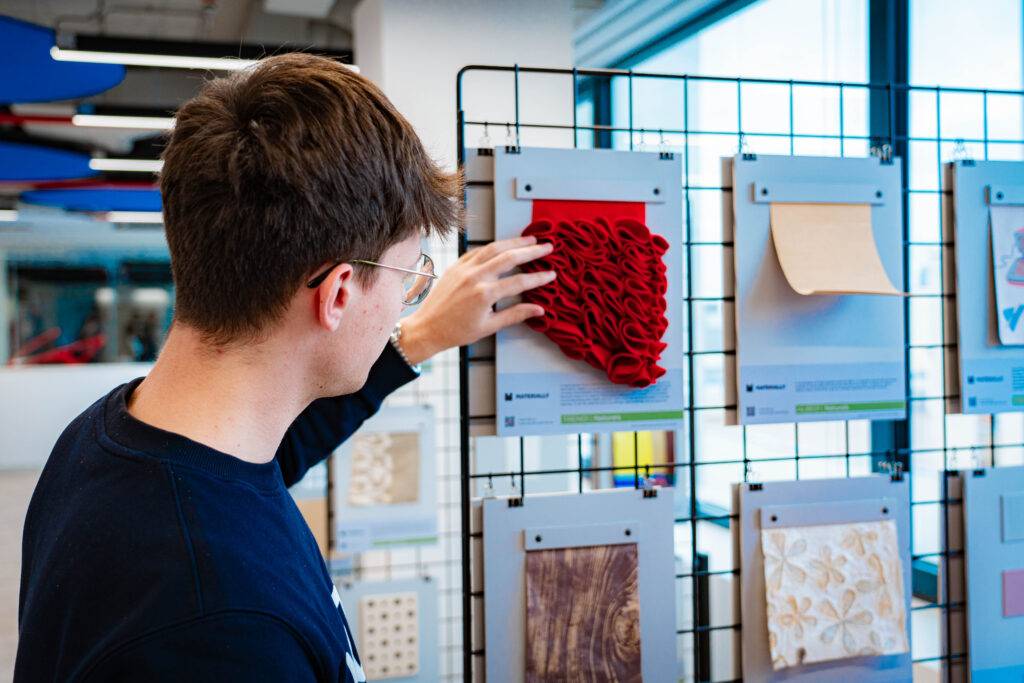 Un hombre observa un panel de muestras de texturas en una exposición.