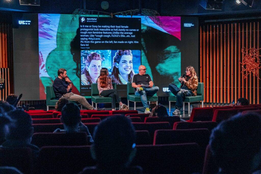 Un panel de discusión en un evento, con cinco personas sentadas en sillas y una pantalla proyectando información detrás.