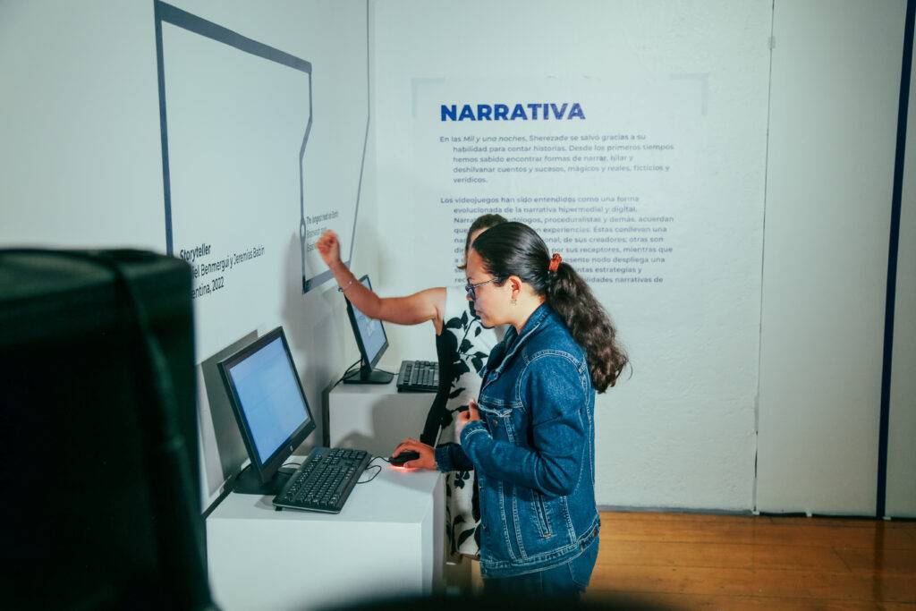 Dos personas interactúan con computadoras en una exposición de arte.
