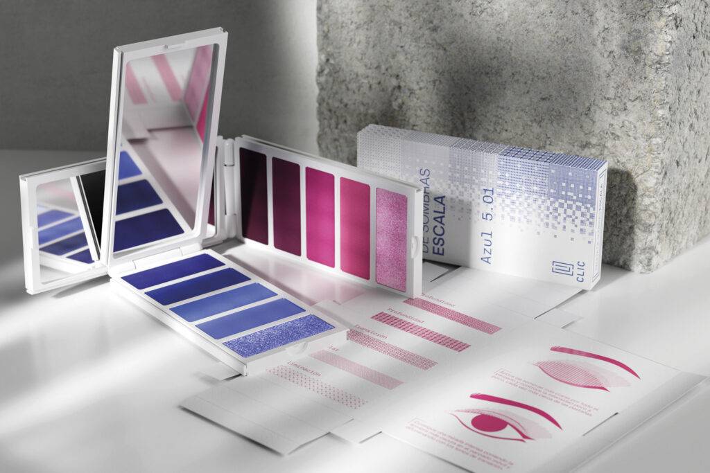 La imagen muestra un conjunto de paletas de maquillaje con tonos de azul y púrpura junto a un manual de instrucciones.