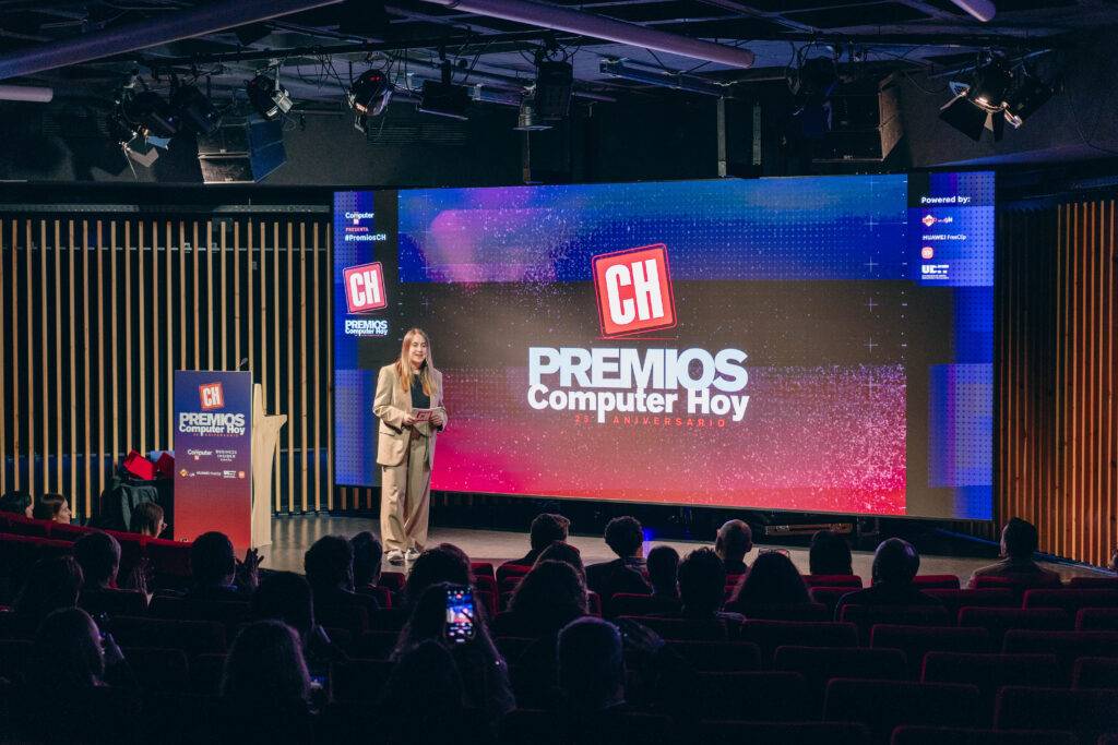 Una mujer presenta los Premios Computer Hoy en un escenario iluminado con un gran fondo digital.