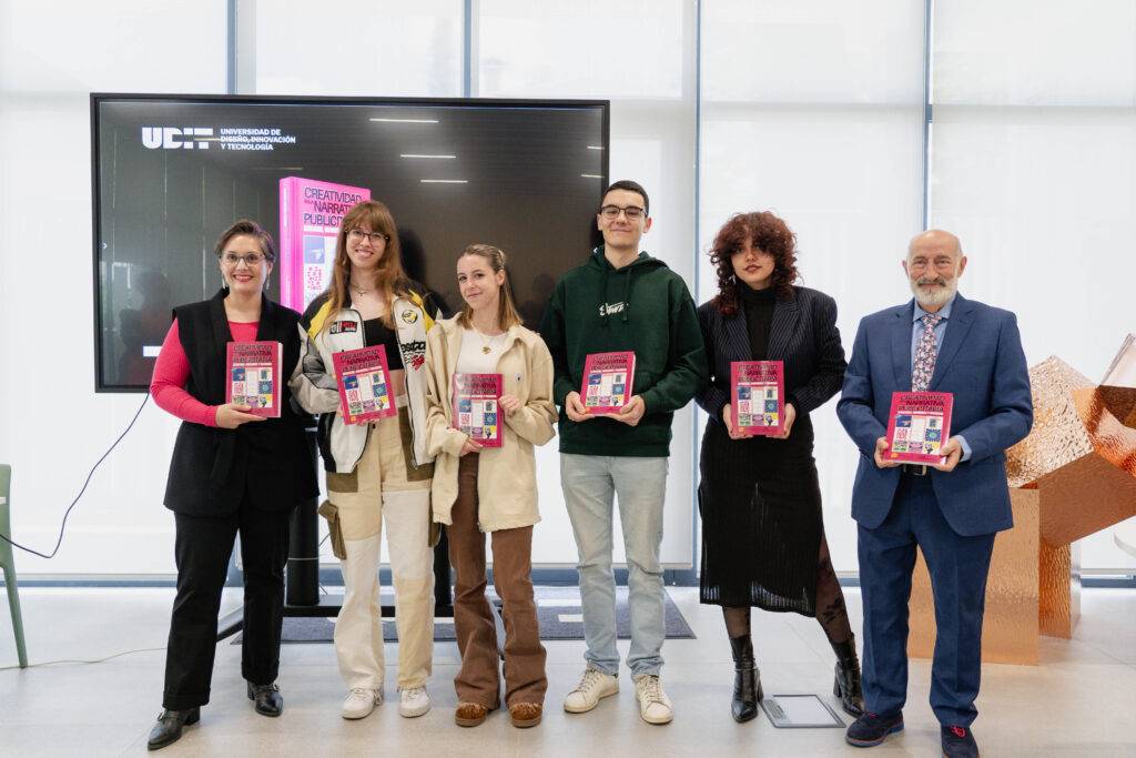 Un grupo de personas sostiene libros en un evento celebrando una entrega o presentación.