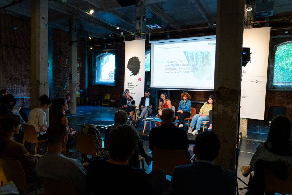 Una conferencia en un espacio moderno con panelistas discutiendo frente a una audiencia.