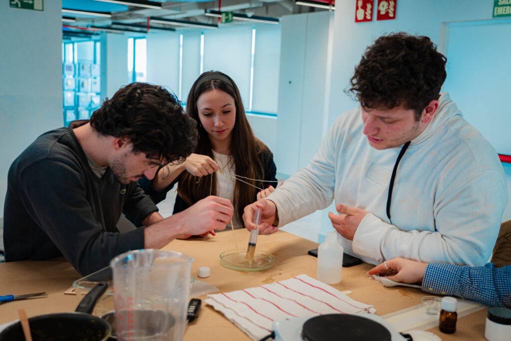 Un grupo de jóvenes experimenta con materiales en una mesa de trabajo.