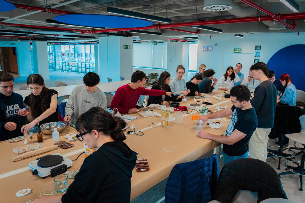 Un grupo de personas trabaja en una mesa larga realizando actividades creativas.