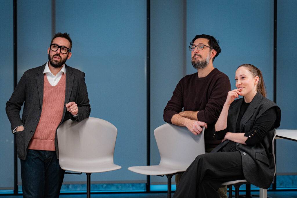 Un grupo de tres personas discutiendo en un entorno moderno y luminoso.