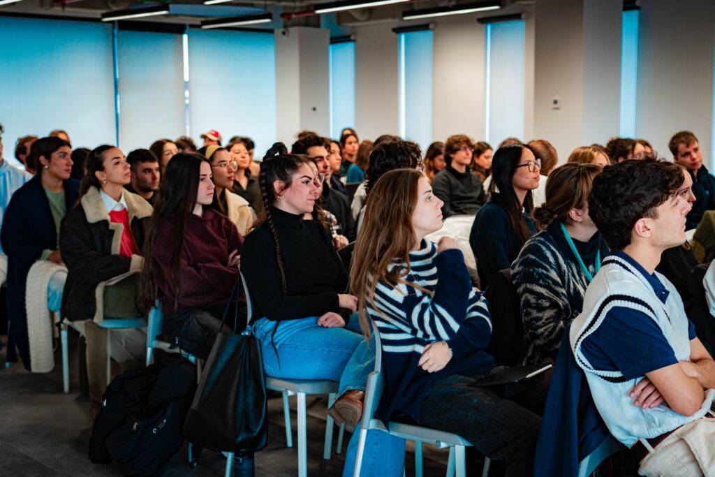 Un grupo de jóvenes sentados en un salón escuchando atentamente una presentación.