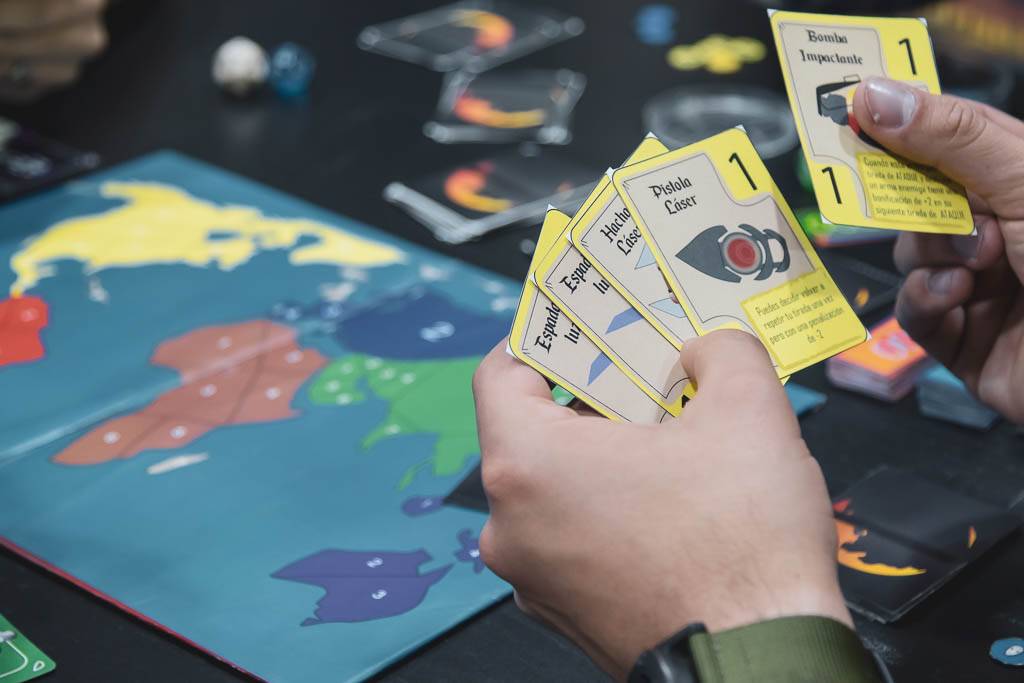 Un grupo de personas juega un juego de mesa, mostrando cartas y un tablero colorido.