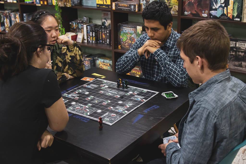 Un grupo de cuatro personas está jugando a un juego de mesa en una tienda de juegos.