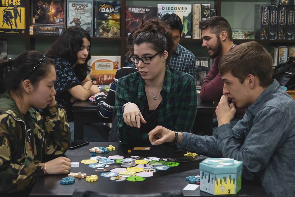 Un grupo de personas juega a un juego de mesa en una tienda especializada.