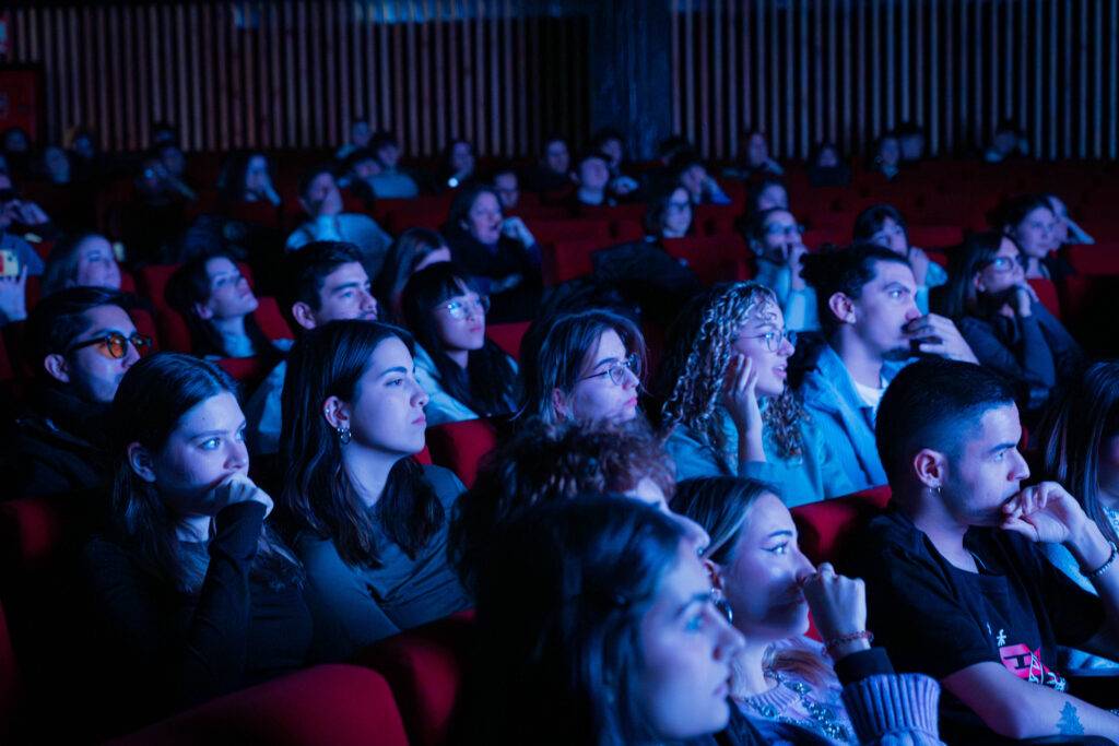 Un grupo de personas sentadas en un cine, observando atentamente una proyección.