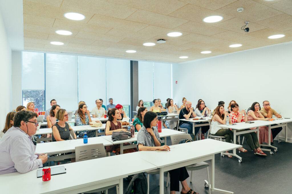 Un grupo de personas escuchando atentamente en una sala de clases moderna.
