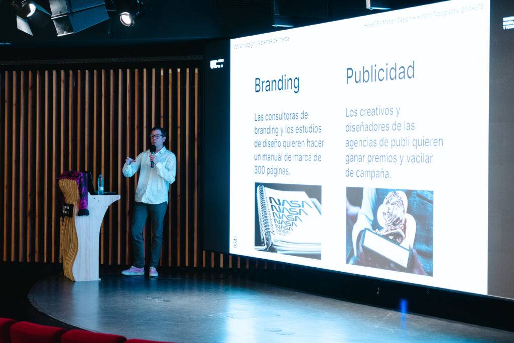 Un presentador expone sobre branding y publicidad en un escenario con pantallas.