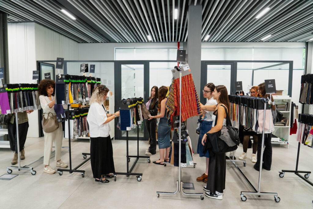 Un grupo de mujeres observa y selecciona productos en un espacio de exhibición con estanterías.