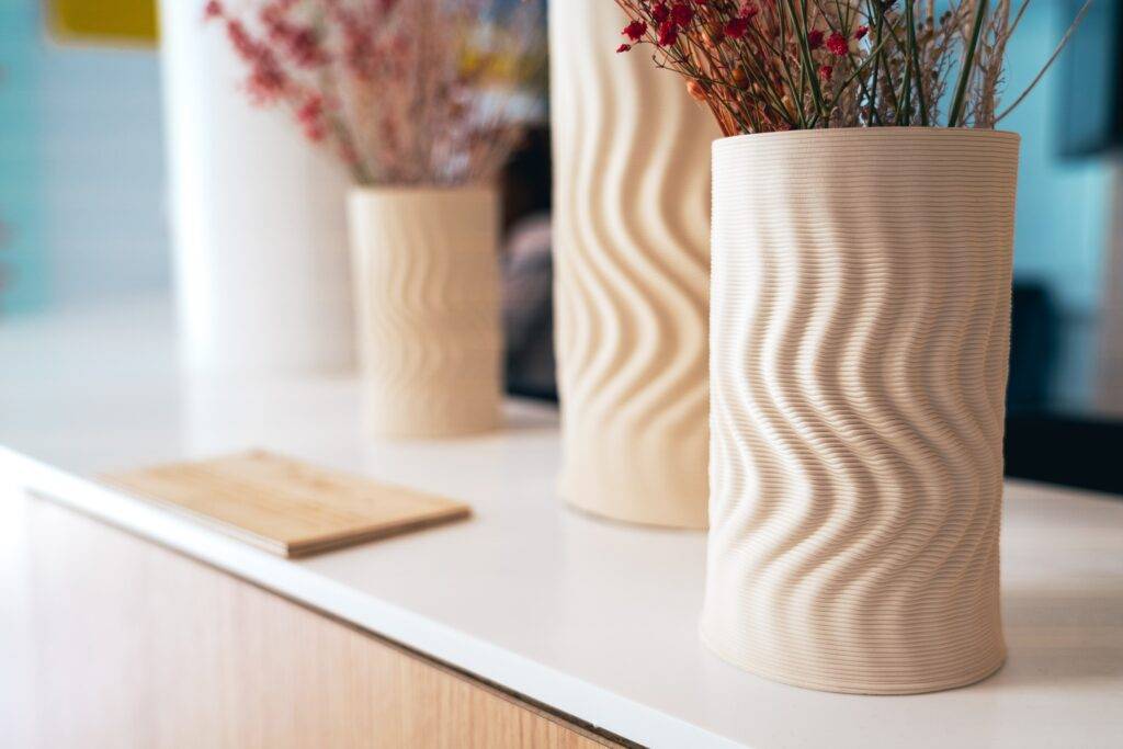 Una serie de jarrones con un diseño ondulado llenos de flores secas sobre una mesa blanca.