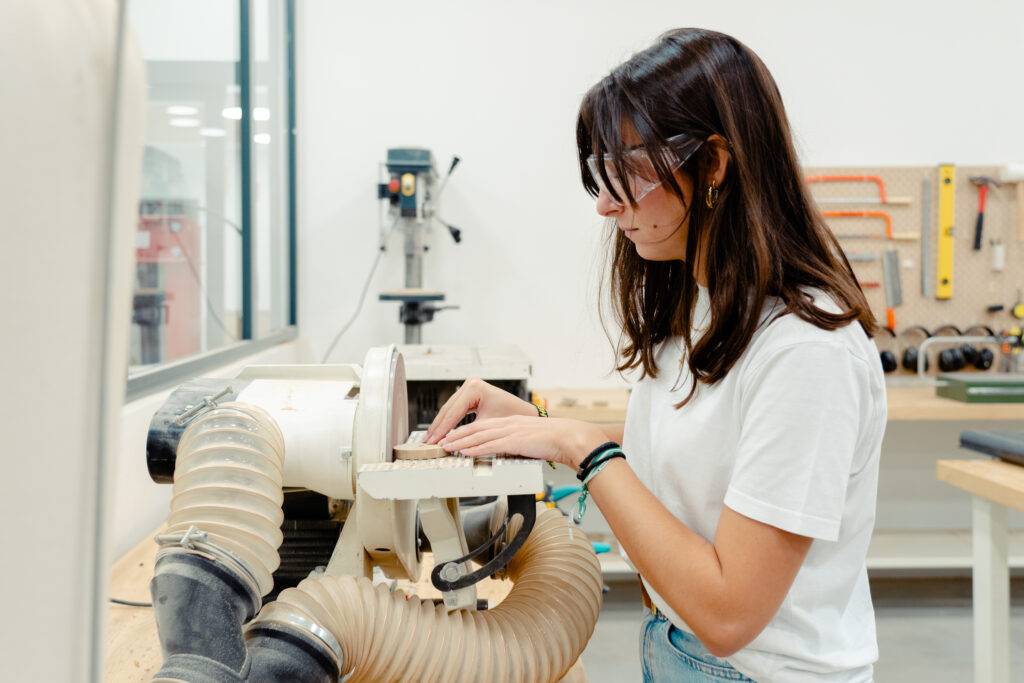 Una joven está utilizando una herramienta en un taller de carpintería.