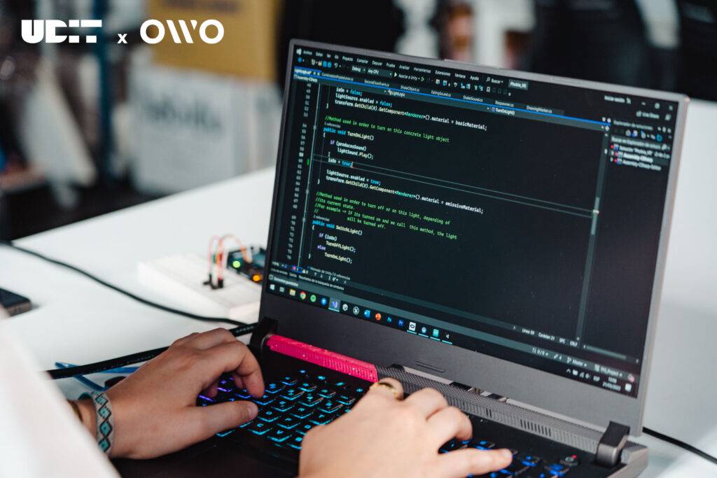 Una persona está programando en una computadora portátil con la pantalla mostrando código.